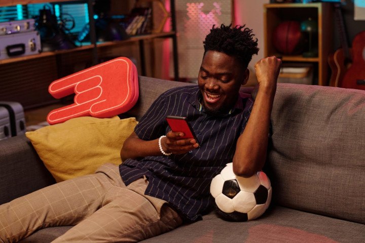 Black man celebrating victory while using smartphone